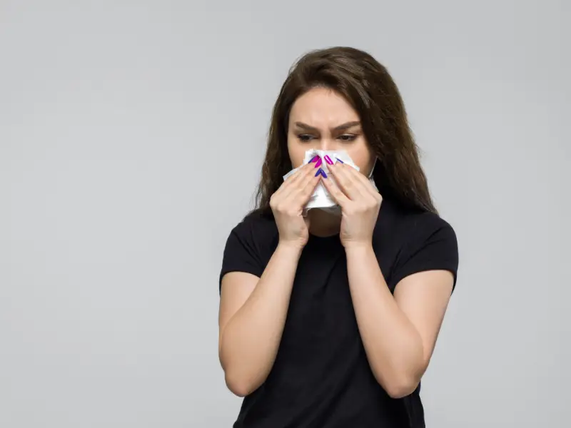 Young woman wiping her nose
